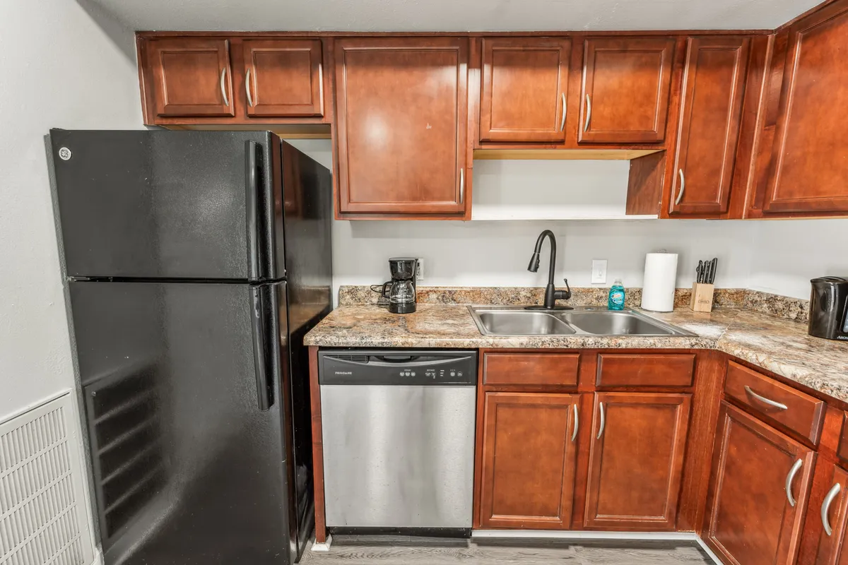A modern kitchen with dark wooden cabinets, granite countertops, and stainless steel appliances. The space feels practical and welcoming, ideal for preparing family meals or grabbing a quick snack before heading out.