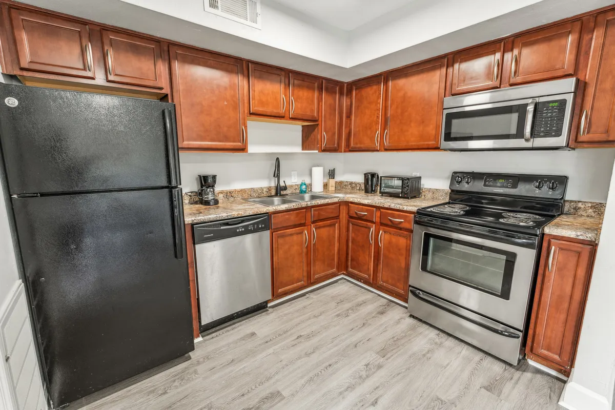 This scene features a kitchen with dark wood cabinetry, a spacious granite countertop, and state-of-the-art stainless steel appliances. The space feels inviting and practical, clearly ready for family gatherings or meal preparation. The design suggests a welcoming environment for cooking and connecting with others.