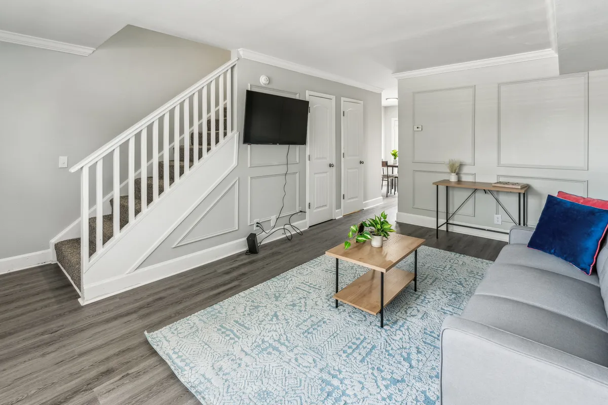 A cozy living space with a staircase, inviting sofa, and coffee table, arranged for comfort and effortless gatherings. The open-plan design hints at spaciousness and flexibility for both quiet moments and lively get-togethers.