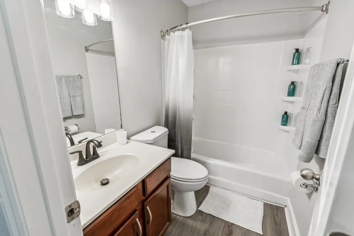 An inviting bathroom featuring a vanity with sink, toilet, a comfortable bathtub, and a mirrored cabinet. The space blends practicality with comfort, perfect for morning routines or evening relaxation.