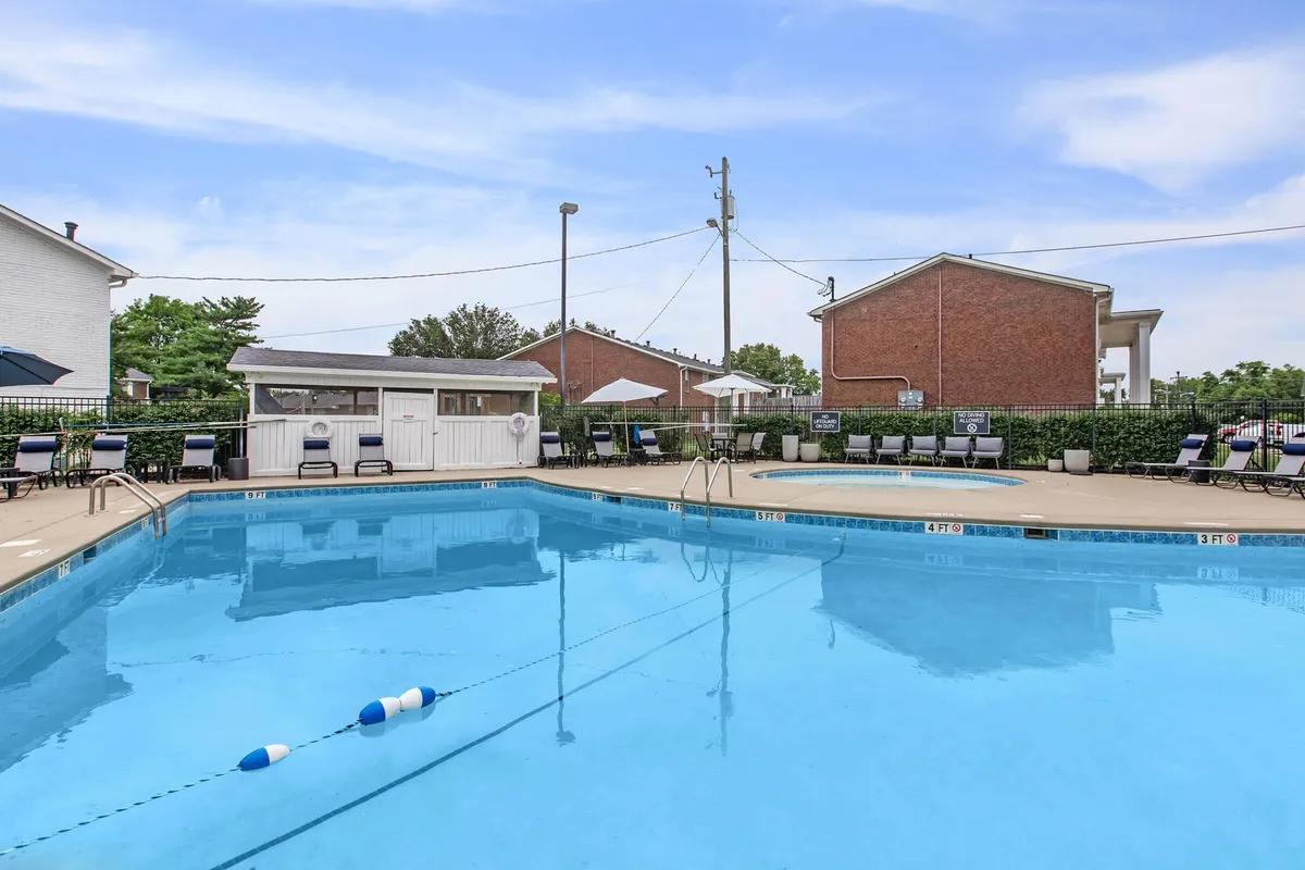 A refreshing outdoor swimming pool area surrounded by lush greenery, with lounge chairs lined up beside the water and a poolside cabana offering shaded relaxation. The scene is tranquil, inviting residents to unwind in a peaceful environment while remaining close to the vibrancy of city life.